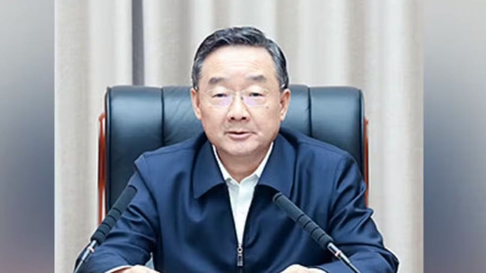 Ex-ministro da Agricultura da China sentado à mesa durante pronunciamento oficial.