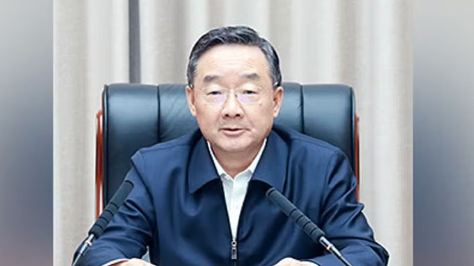 Ex-ministro da Agricultura da China sentado à mesa durante pronunciamento oficial.