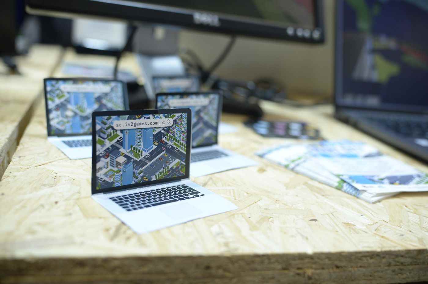 Miniaturas de laptops exibindo a plataforma Smart City no estande do Grupo iv2, promovendo a realidade virtual na Feira do Empreendedor.