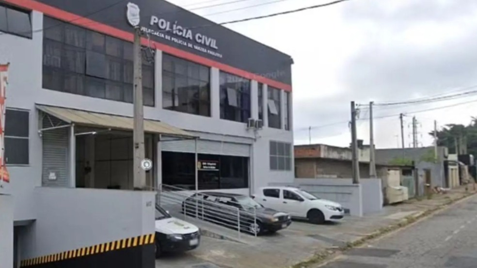 Fachada da Delegacia de Polícia Civil de Várzea Paulista com viaturas estacionadas na entrada e céu nublado ao fundo. Fachada da Delegacia de Polícia Civil de Várzea Paulista com viaturas estacionadas na entrada e céu nublado ao fundo.