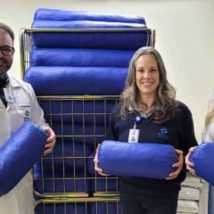 Equipe do Hospital São Vicente de Jundiaí segura coxins azuis feitos com uniformes reciclados em ação sustentável.