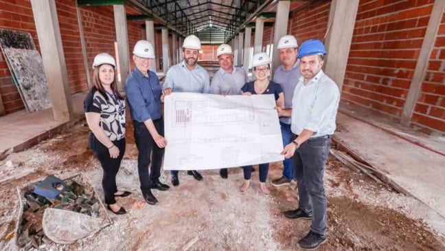 Autoridades e empresários observam as obras de ampliação do IFSP Jundiaí e seguram a planta do projeto dentro do novo prédio em construção.