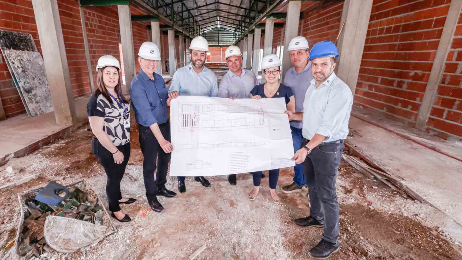 Autoridades e empresários observam as obras de ampliação do IFSP Jundiaí e seguram a planta do projeto dentro do novo prédio em construção.