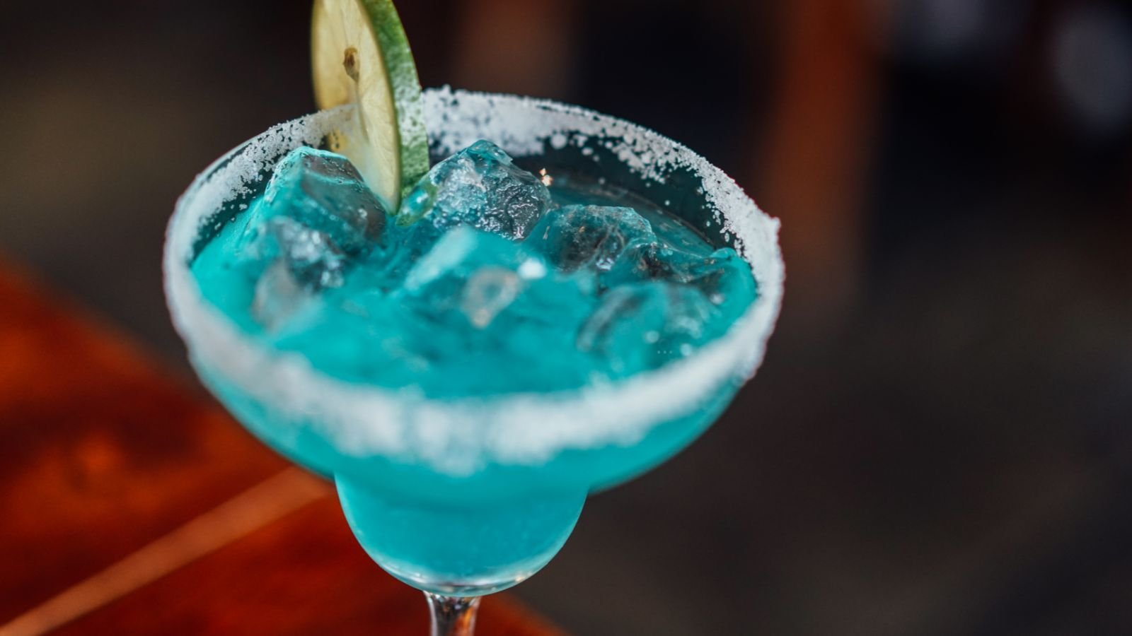 Taça de coquetel azul com gelo, borda de sal e fatia de limão, simbolizando consumo de bebidas alcoólicas e os riscos de intoxicação por metanol.