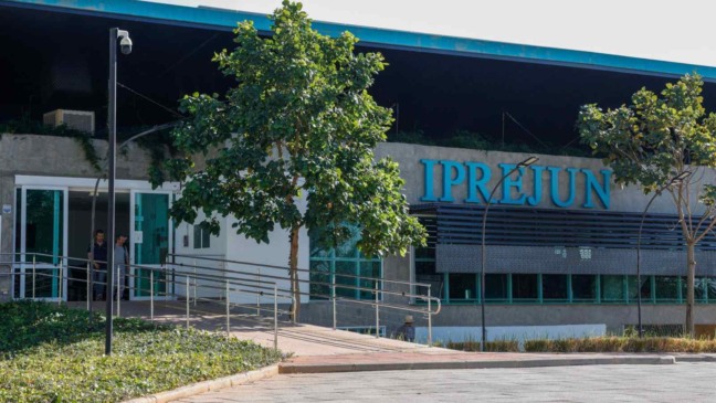 Fachada do prédio do IPREJUN em Jundiaí, com letreiro azul e entrada acessível com rampa cercada por árvores.