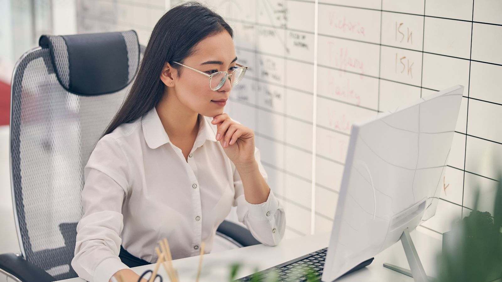 Jovem aprendiz no setor administrativo trabalha em frente ao computador em um escritório moderno.