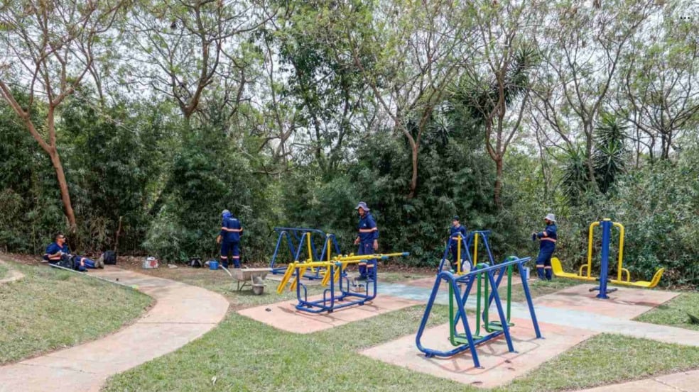 Trabalhadores da Prefeitura de Jundiaí fazem manutenção e pintura nos equipamentos da academia ao ar livre da Praça Petronilha Rosa de Assis, cercada por vegetação. Trabalhadores da Prefeitura de Jundiaí fazem manutenção e pintura nos equipamentos da academia ao ar livre da Praça Petronilha Rosa de Assis, cercada por vegetação.