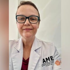 Dra. Vanessa Pesciotto, médica cardiologista do AME Jundiaí, usando jaleco branco com o logotipo do ambulatório.