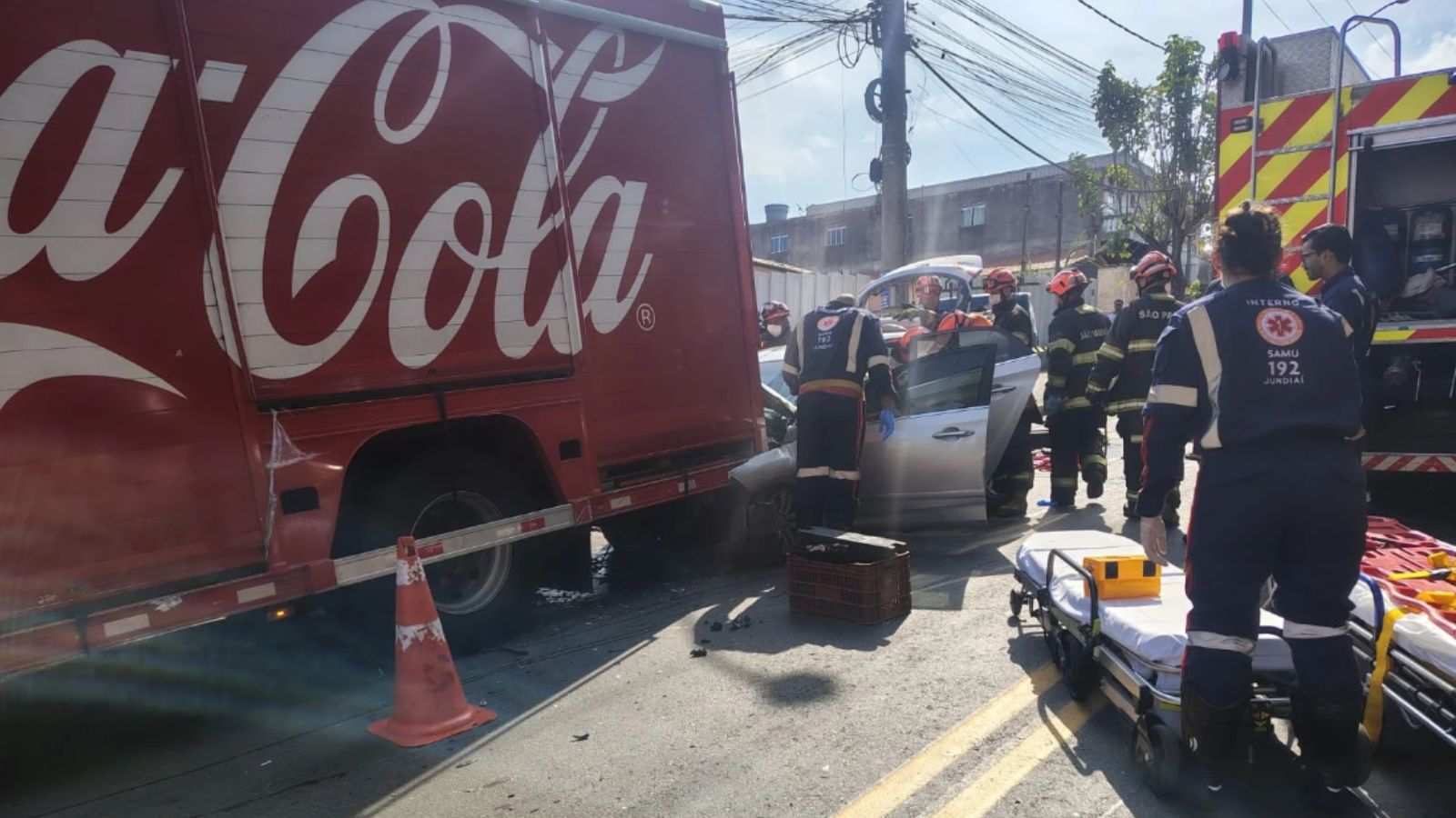 Equipes do SAMU e bombeiros socorrem motorista preso nas ferragens após colisão entre carro e caminhão da Coca-Cola em Jundiaí.