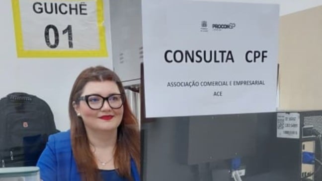 Atendente da ACE Jundiaí no guichê 01 do Procon, com placa indicando serviço de consulta de CPF durante o Mutirão Limpa Nome.