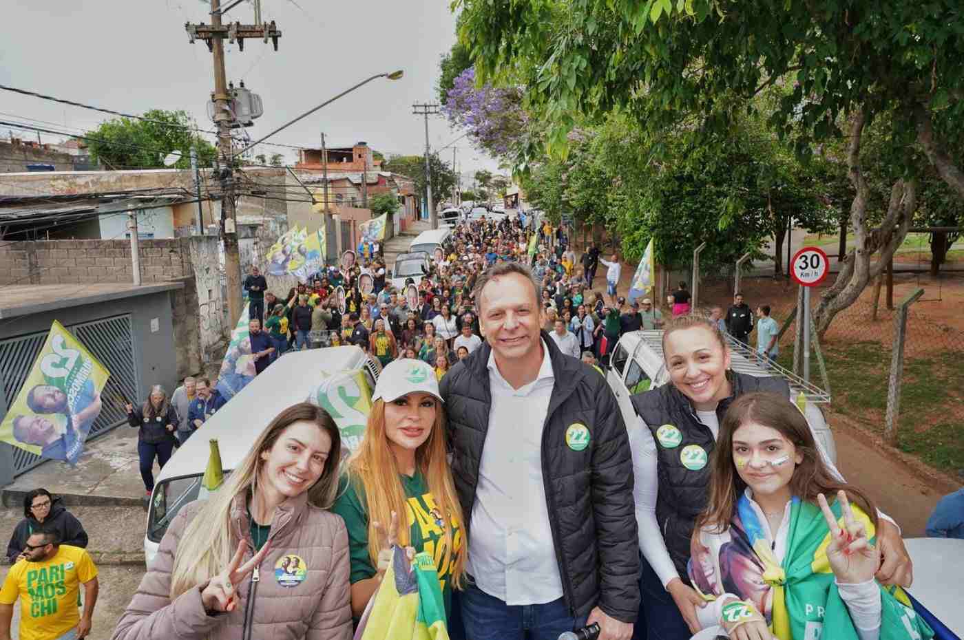 Candidato José Antonio Parimoschi em caminhada de campanha na Região Sul de Jundiaí, rodeado por apoiadores e bandeiras.