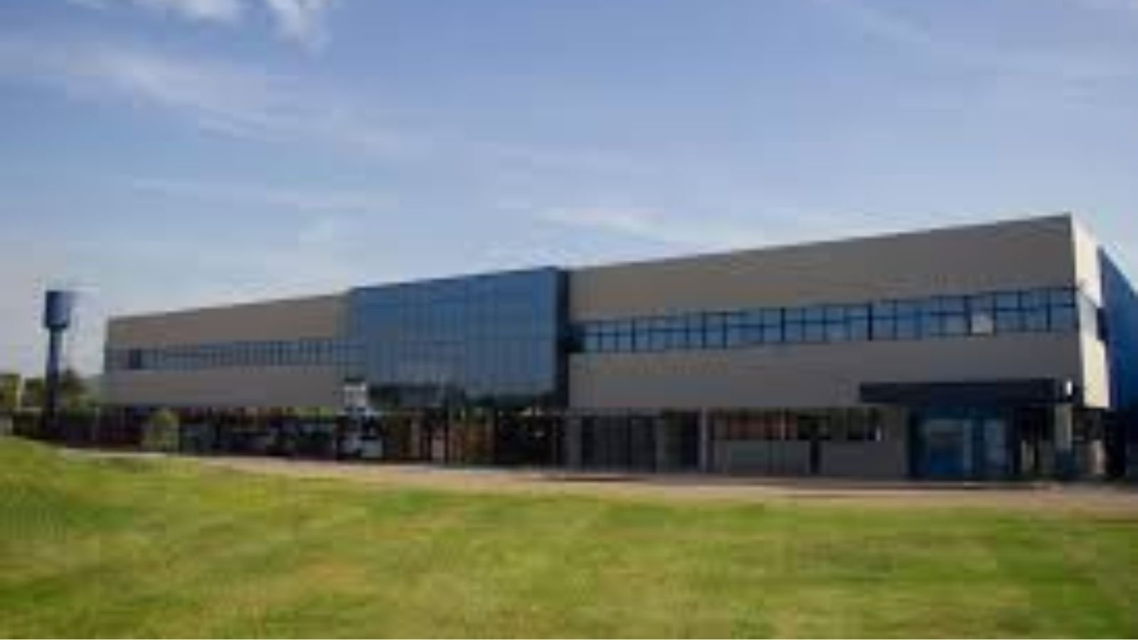 Fachada da VTC Tecnologia em Vidros Temperados em Itupeva, com janelas espelhadas e gramado em primeiro plano sob céu azul.