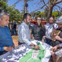 Prefeito e equipe técnica analisam o mapa do projeto de revitalização do Parque dos Ipês, em reunião ao ar livre.