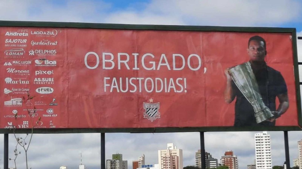 Outdoor em Jundiaí homenageia o técnico Fausto Dias, com a frase “Obrigado, Fausto Dias!” e a imagem dele segurando um troféu.