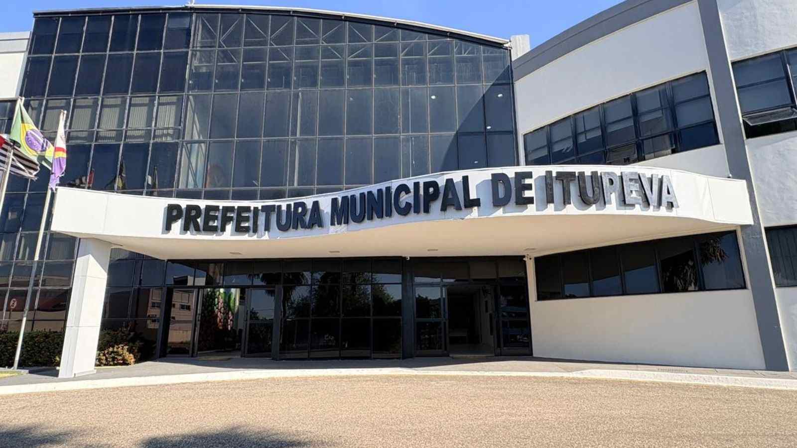 Prédio da Prefeitura Municipal de Itupeva com entrada principal e bandeiras na fachada.