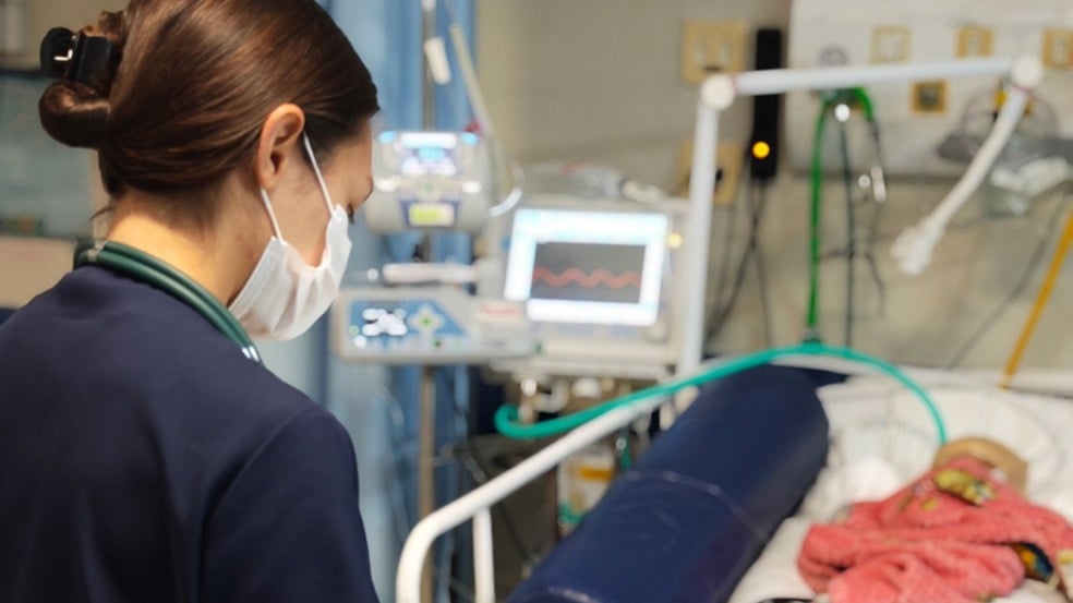 Profissional de saúde monitora bebê em UTI neonatal durante residência multiprofissional. Profissional de saúde monitora bebê em UTI neonatal durante residência multiprofissional.