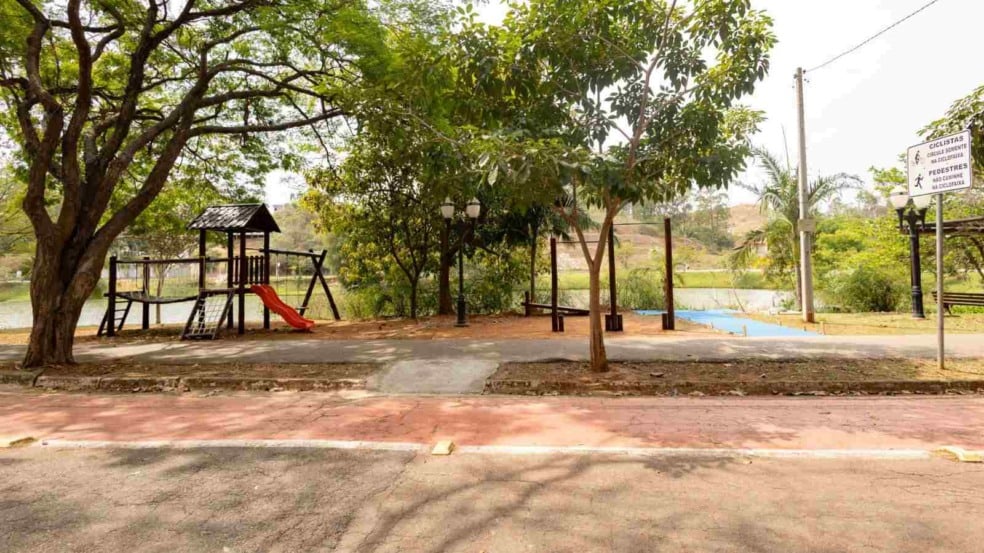 Praça do Vale Azul em Jundiaí com árvores, brinquedos infantis, escorregador laranja e pista de caminhada próxima ao lago.