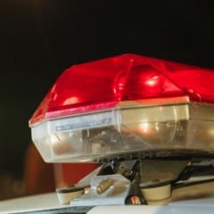 Sirene vermelha de viatura policial acesa durante a noite, em close-up.