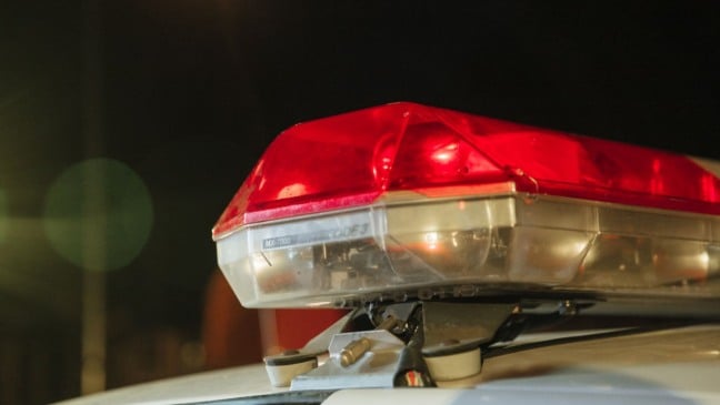 Sirene vermelha de viatura policial acesa durante a noite, em close-up.