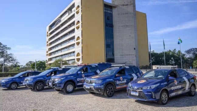 Viaturas da Guarda Municipal de Jundiaí estacionadas em frente ao Paço Municipal, com bandeiras e prédio ao fundo. Viaturas da Guarda Municipal de Jundiaí estacionadas em frente ao Paço Municipal, com bandeiras e prédio ao fundo.