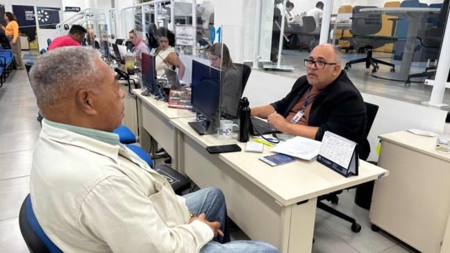 Homem idoso é atendido por funcionário no balcão do Espaço Jundiaí Empreendedora, em busca de oportunidades de trabalho na terceira idade.