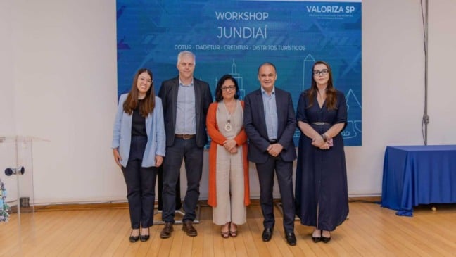 Cinco autoridades posam para foto em frente ao painel do Workshop Valoriza São Paulo, em Jundiaí, evento que apresentou ações e programas para o setor turístico.