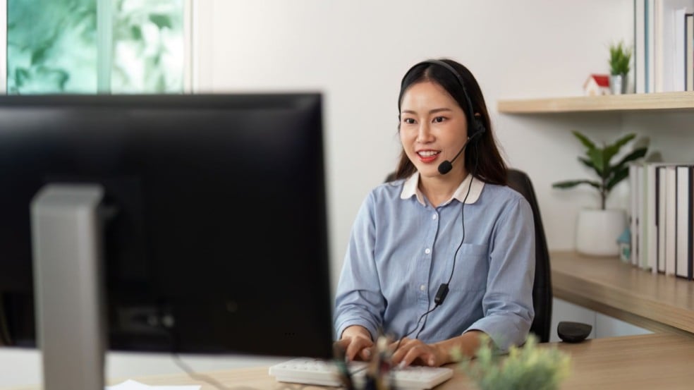 Mulher atendente de call center trabalhando no computador e sorrindo durante atendimento remoto em home office. Mulher atendente de call center trabalhando no computador e sorrindo durante atendimento remoto em home office.