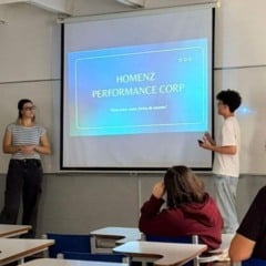 Grupo de estudantes da ESAMC Jundiaí apresenta um projeto diante da turma, com um slide projetado intitulado “Homenz Performance Corp”.