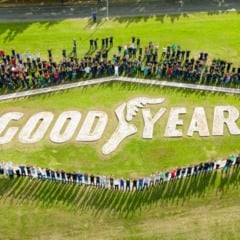 Vista aérea de colaboradores da Goodyear formando um círculo ao redor do logotipo da empresa no gramado, com a palavra “GOODYEAR” e o símbolo da asa alada.