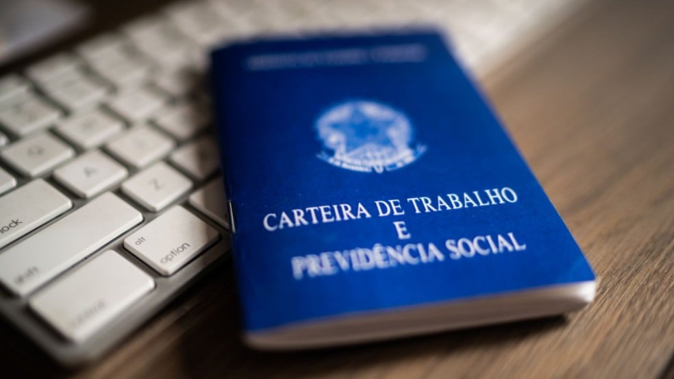 Carteira de Trabalho azul sobre um teclado branco, representando emprego e mercado de trabalho no Brasil. Carteira de Trabalho azul sobre um teclado branco, representando emprego e mercado de trabalho no Brasil.