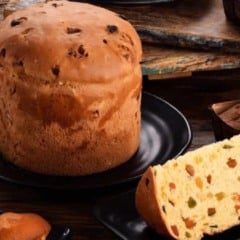 Panetone artesanal Romanato com frutas cristalizadas em destaque sobre prato preto.