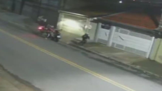 Cena capturada por câmera de segurança mostra dois homens em uma moto assaltando uma motociclista na Avenida Pacaembu, em Várzea Paulista.