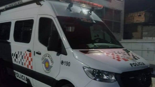 Viatura da Polícia Militar de São Paulo estacionada à noite, com luz de emergência acesa e identificação de Base Comunitária Móvel.