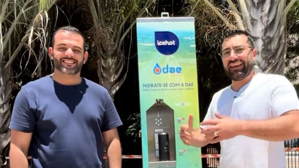 Dois homens sorriem ao lado de um ponto de hidratação recém-instalado na Avenida 9 de Julho, em Jundiaí, com palmeiras ao fundo. Dois homens sorriem ao lado de um ponto de hidratação recém-instalado na Avenida 9 de Julho, em Jundiaí, com palmeiras ao fundo.