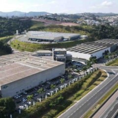 Imagem aérea da unidade da Brasilata em Jundiaí, com galpões industriais, áreas verdes e a rodovia à direita.