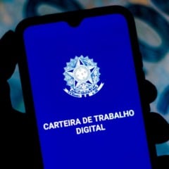 Celular mostrando o aplicativo Carteira de Trabalho Digital com o brasão do Brasil, em frente a notas de dinheiro desfocadas ao fundo.
