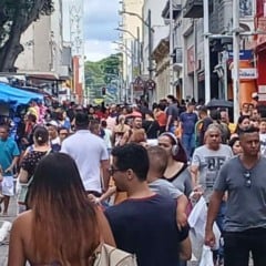 Multidão circula pelo centro de Jundiaí em dia de comércio movimentado, com pedestres, lojas abertas e barracas ao longo da rua.