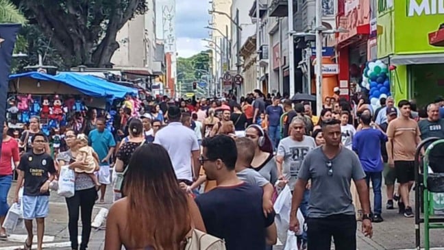Multidão circula pelo centro de Jundiaí em dia de comércio movimentado, com pedestres, lojas abertas e barracas ao longo da rua.