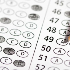 Pessoa preenchendo cartão de respostas de prova de múltipla escolha com lápis, representando um processo seletivo ou concurso.