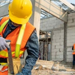 Operários da construção civil usando capacete e colete refletivo enquanto trabalham em um canteiro de obras em Jundiaí.