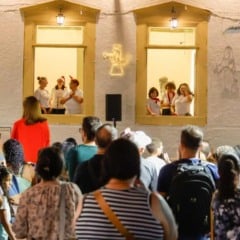 Coral se apresenta nas janelas iluminadas do Solar do Barão em Jundiaí durante evento de Natal, com público reunido na calçada assistindo.