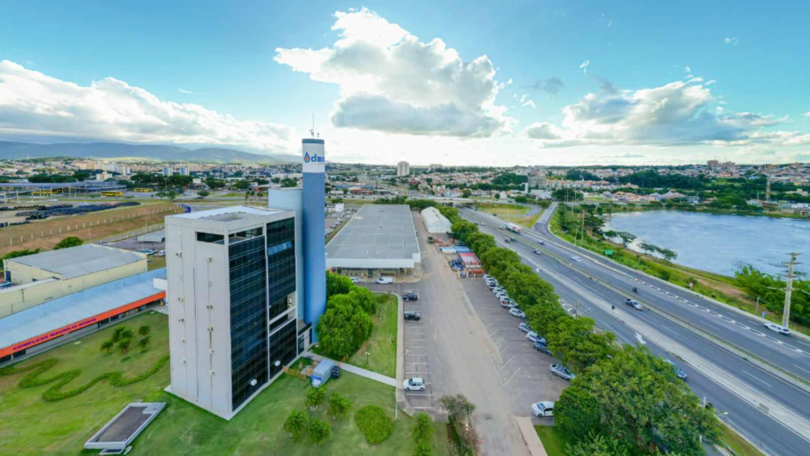 Imagem aérea da sede da DAE Jundiaí, mostrando o prédio administrativo, a torre azul, a Rodovia Anhanguera e o Parque da Cidade ao fundo.