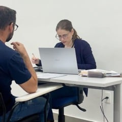 Mulher realiza atendimento e triagem de currículos de um candidato durante o mutirão de empregos do programa Emprego da Gente em Jundiaí.