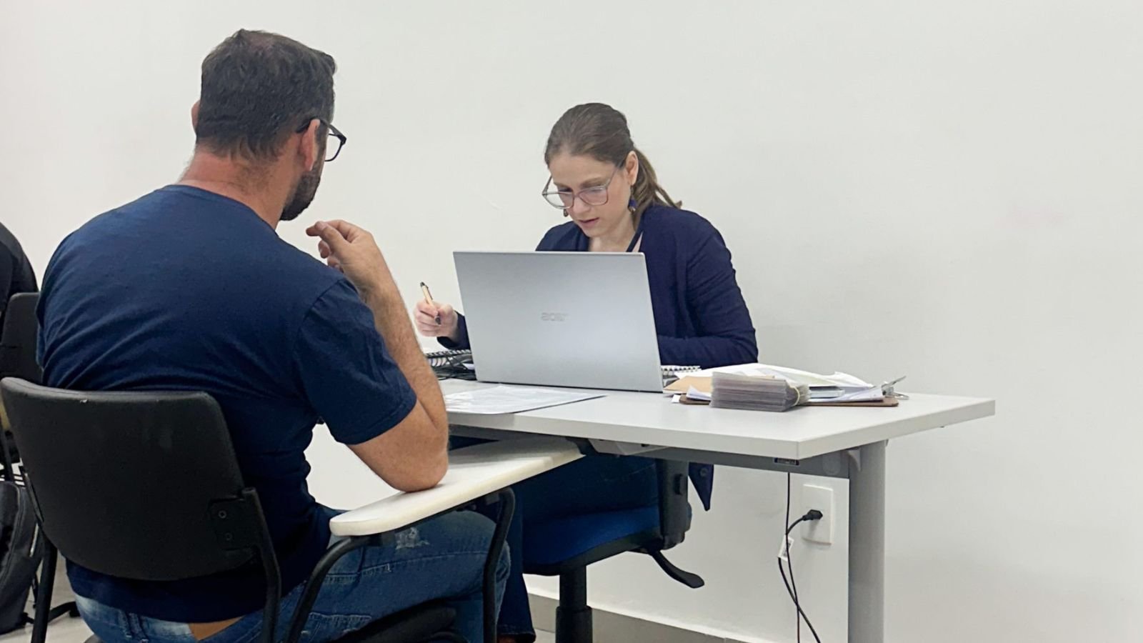 Mulher realiza atendimento e triagem de currículos de um candidato durante o mutirão de empregos do programa Emprego da Gente em Jundiaí.