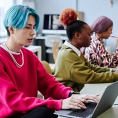 Jovens da Geração Z trabalhando em laptops em um escritório moderno, simbolizando diversidade e inovação tecnológica.