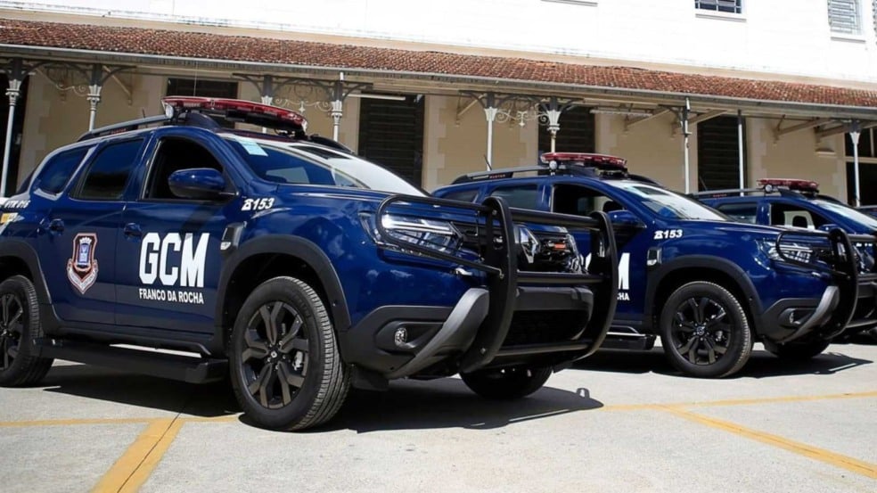 Viaturas da Guarda Civil Municipal de Franco da Rocha estacionadas, com identificação da corporação e luzes de emergência, em frente a um prédio de fachada antiga.