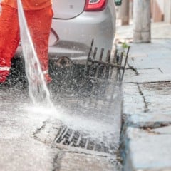 Funcionário da Prefeitura realiza limpeza de boca de lobo com jato de água para desobstruir a drenagem urbana em Jundiaí.