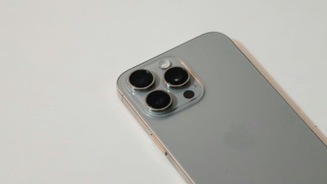 Close da traseira de um iPhone prata, evidenciando o módulo com três lentes de câmera.