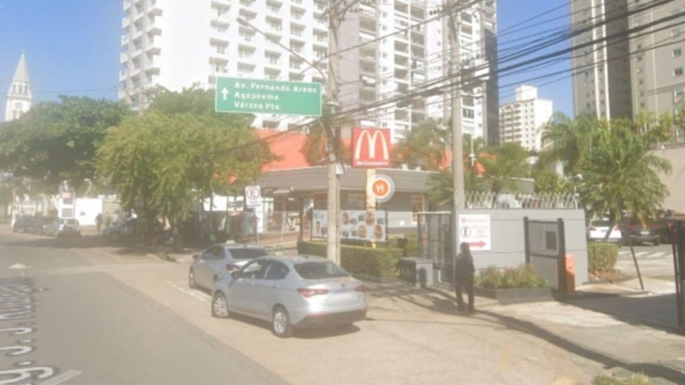Fachada de um McDonald’s em Jundiaí com carros estacionados na rua, prédios residenciais ao fundo e placa indicando direção para Avenida Fernando Arens e Várzea Paulista. Fachada de um McDonald’s em Jundiaí com carros estacionados na rua, prédios residenciais ao fundo e placa indicando direção para Avenida Fernando Arens e Várzea Paulista.