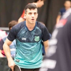 Michel Sartorato, do Time Jundiaí, joga tênis de mesa durante competição estadual, vestindo uniforme azul e verde.